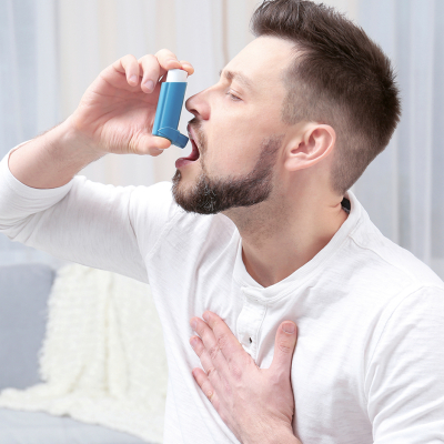 Young man using asthma inhaler at home